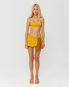model wearing yellow bikini top and pareo mini skirt 